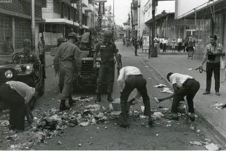 Soldados norteamericanos observan a civiles recogiendo basura