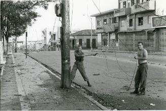 Dos soldados cortando poste del tendido eléctrico