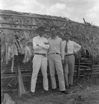 Tres hombres frente a un rancho