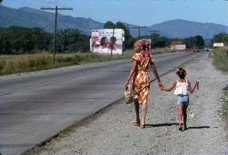 Mujer y niña caminando por la carretera de Bonao