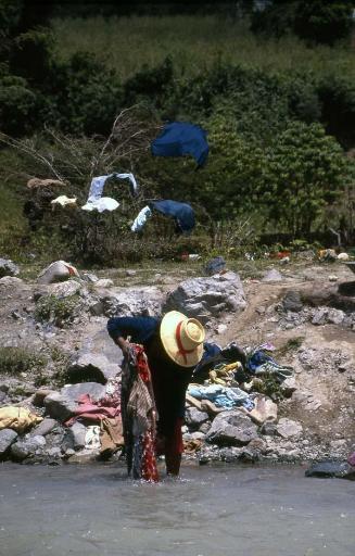 Mujer lavando ropa en el río