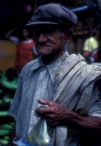 Anciano con guineos en mercado